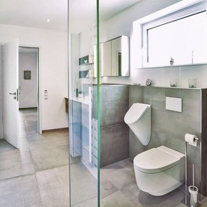 Ein modernes Badezimmer mit einer gläsernen Duschwand, eleganten Fliesen und einem minimalistischen Design.