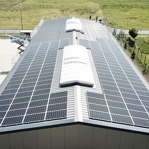 Moderne Solaranlage auf einem Dach in der Natur Solarzellen auf einem Dach, die effizient Sonnenlicht einfangen, während im Hintergrund eine ruhige, grüne Umgebung sichtbar ist.
