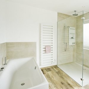 Schickes Badezimmer mit Glasdusche und minimalistischer Einrichtung Helles Badezimmerdesign mit einer großen Dusche, freistehender Badewanne und einem Handtuchhalter, der einen Hauch von Eleganz verleiht.