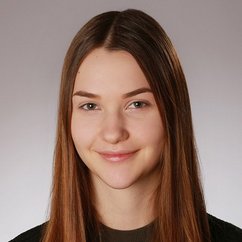 Eine junge Frau mit langen, glatten Haaren und einem sanften Lächeln, vor einem neutralen Hintergrund.