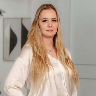 Stilvolles Porträt einer Frau in heller Bluse In einem stilvollen Raum posiert eine Frau mit langen, glatten Haaren, die in einem eleganten, weißen Hemd gekleidet ist.