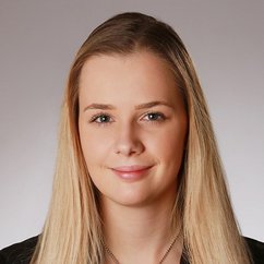 Eine junge Frau mit langen, blonden Haaren und einem freundlichen Lächeln blickt direkt in die Kamera.